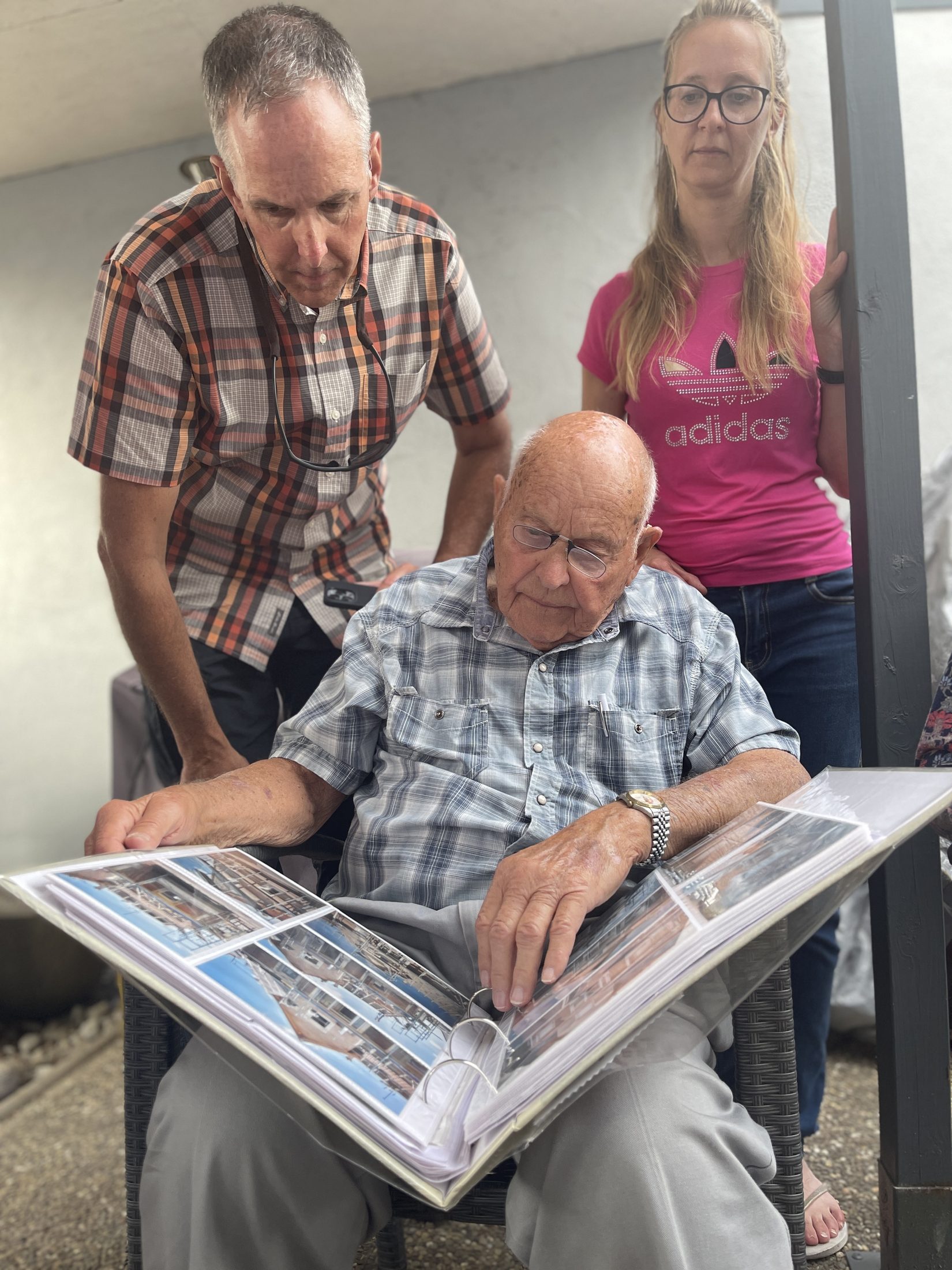 42nd Rainbow Division veteran Bud Gahs with his nephew Scott and the Schweighouse family reviewing their photographs at the home he fought in, Schweighouse-sur-Moder, Alsace